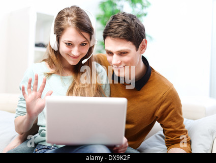 Happy young couple is talking to its friends or family through the computer with video chat Stock Photo