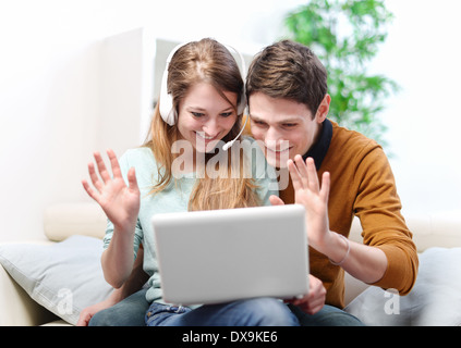 Happy young couple is talking to its friends or family through the computer with video chat Stock Photo