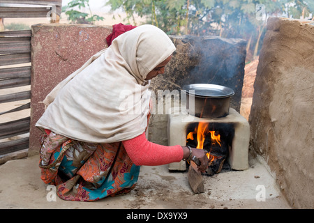 India, Uttar Pradesh, Agra, woman boiling water on outside fire using cow dung and wood as fuel Stock Photo