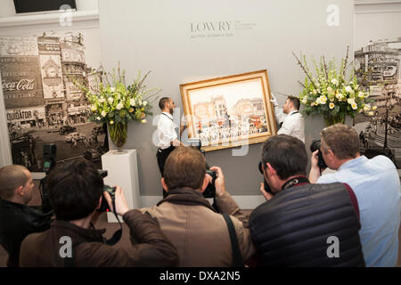 Sotheby's, London, UK. March 21st 2014. During a photocall, Sotheby's workers hang LS Lowry's Piccadilly Circus, painted in 1961 and expected to fetch between £4-6 million at auction on March 25th as the AJ Thompson collection, the most comprehensive of Lowry's work, goes on sale. Credit:  Paul Davey/Alamy Live News Stock Photo