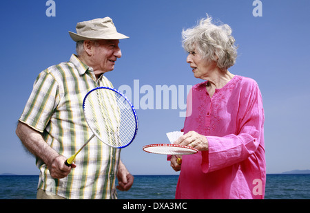 Senior couple on beach with badminton racquets and ball Stock Photo