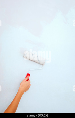 Hand with roller brush painting wall. Stock Photo