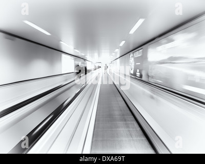 Person on a moving through a tunnel walkway escalator Stock Photo