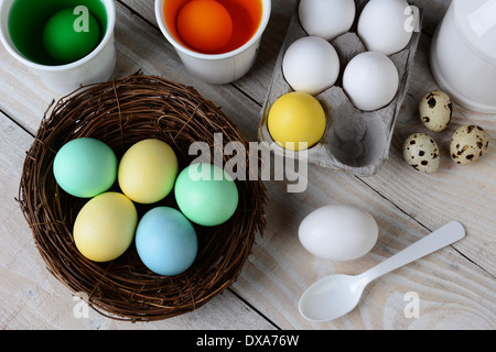 High angle view of Dying Easter Eggs. Dyed eggs in a nest with eggs in dye solution and other eggs ready to be dunked. Stock Photo