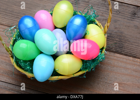 High Angle view of a basket filled with colorful plastic Easter eggs. Horizontal format on a rustic wood background. Stock Photo
