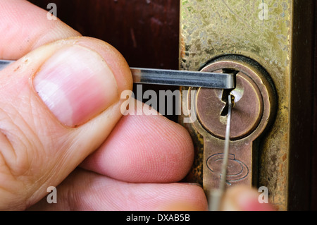 A man uses lockpicking tools to pick the lock of a house front door Stock Photo