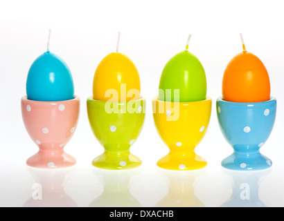 multicolored easter eggs candles in eggcups Stock Photo