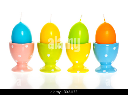 multicolored easter eggs candles in eggcups on white background Stock Photo