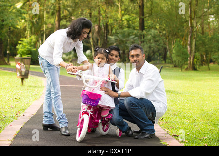 indian family teaching their kids cycling in the outdoor park Stock Photo