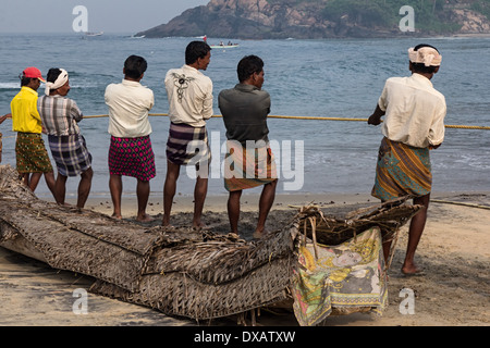 Fishermen pulling in fishing rope at Lighthouse Beach in Kovalam, Kerala, India Stock Photo