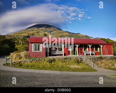 View of the volcano Mount Taranaki (Mt Egmont) Egmont National Park and the red camphouse corrugated iron building Stock Photo