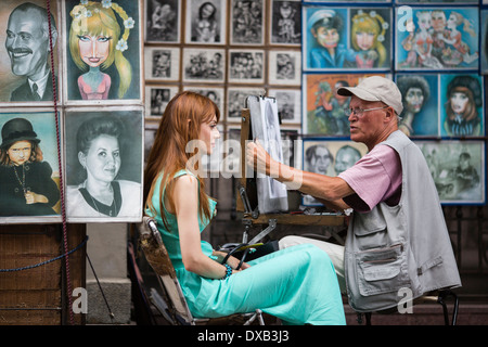 Beautiful young woman having portrait drawn by artist in Arbat Street, Moscow, Russia Stock Photo