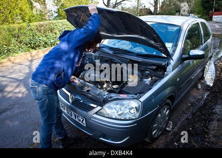 Woman looking under bonnet of broken down car Stock Photo