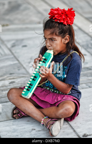 A girl playing melodica in the street of Athens, Greece Stock Photo