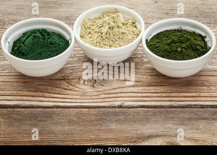 kelp, chlorella and Hawaiian spirulina powders - nutritional supplements from a sea - ceramic bowls against grained wood Stock Photo