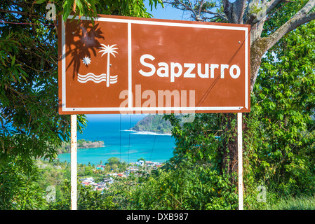 Sign at the entrance to Sapzurro with the town and bay visible below near Capurgana, Colombia Stock Photo