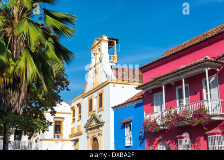 Historic white colonial church standing next to blue and pink historic buildings in Cartagena, Colombia Stock Photo