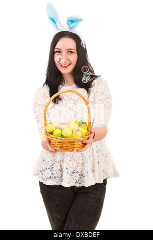 Happy woman with blue bunny ears holding Easter basket and soap bubbles being blow out against white background Stock Photo