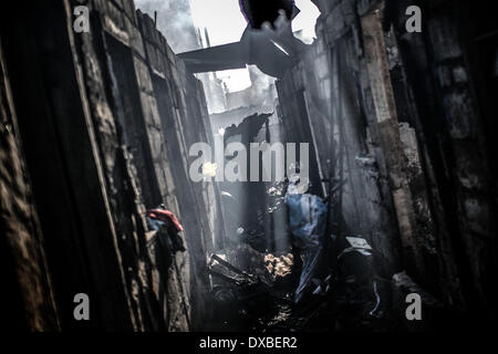 Caloocan, Philippines. 23rd Mar, 2014. A resident collects scrap metal from the rubble of burnt shanties after a fire gutted a residential area in Caloocan city, north of Manila, Philippines, March 23, 2014. At least 1700 families have been left homeless after 3 separate fires gutted 700 homes in a span of 24 hours. The fires took place as the country observes Fire Prevention Month.Photo: Ezra Acayan/NurPhoto Credit:  Ezra Acayan/NurPhoto/ZUMAPRESS.com/Alamy Live News Stock Photo