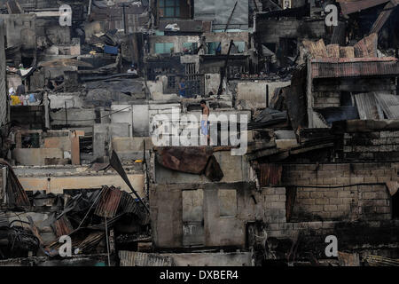 Caloocan, Philippines. 23rd Mar, 2014. A resident walks amidst rows of burnt houses after a fire gutted a residential area in Caloocan city, north of Manila, Philippines, March 23, 2014. At least 1700 families have been left homeless after 3 separate fires gutted 700 homes in a span of 24 hours. The fires took place as the country observes Fire Prevention Month.Photo: Ezra Acayan/NurPhoto Credit:  Ezra Acayan/NurPhoto/ZUMAPRESS.com/Alamy Live News Stock Photo