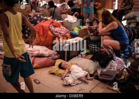 Caloocan, Philippines. 23rd Mar, 2014. Displaced residents take shelter in canopies setup outside the village hall after a fire gutted a residential area in Caloocan city, north of Manila, Philippines, March 23, 2014. At least 1700 families have been left homeless after 3 separate fires gutted 700 homes in a span of 24 hours. The fires took place as the country observes Fire Prevention Month.Photo: Ezra Acayan/NurPhoto Credit:  Ezra Acayan/NurPhoto/ZUMAPRESS.com/Alamy Live News Stock Photo