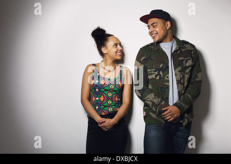 Happy young man and woman looking at each other smiling. Young couple in love against grey background. Stock Photo