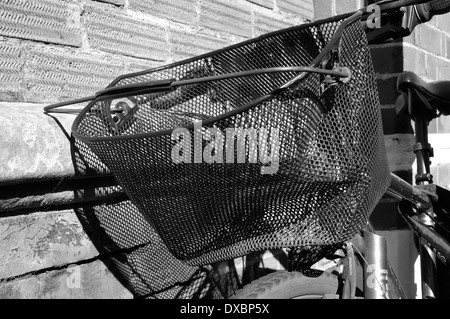 black wire basket on front of bicycle casting a mesh shadow on brick wall behind Stock Photo