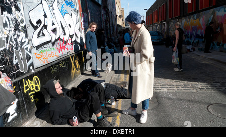 Young woman in conversation with man on the pavement in Brick Lane in spring Tower Hamlets, East End London England KATHY DEWITT Stock Photo