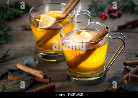 Two hot whiskey, rum, apple or brandy toddy cocktail drinks with cinnamon set on rustic wood Stock Photo