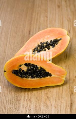 Carica papaya halves on a wooden surface. Cross section of Pawpaw fruit. Stock Photo