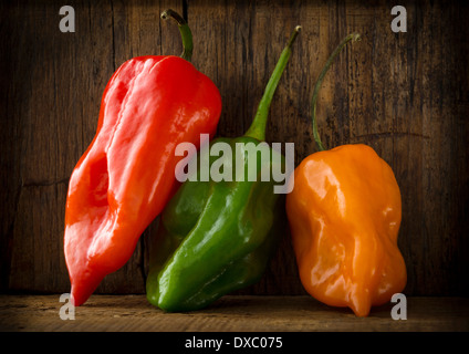 Three hot peppers on wooden background Stock Photo