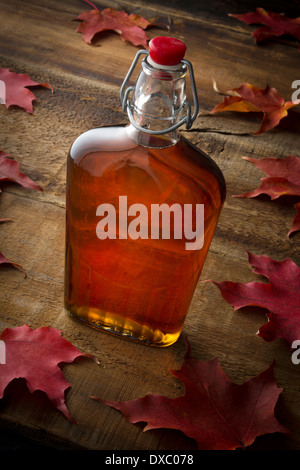 Organic maple syrup on wooden background with maple leaves Stock Photo