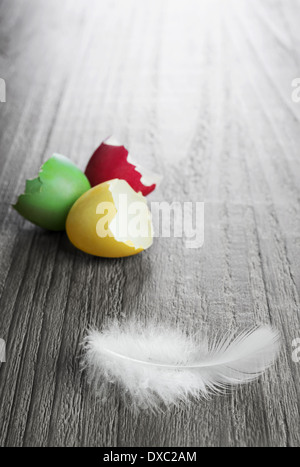 multicolored easter eggs and white feather on vintage wooden table Stock Photo