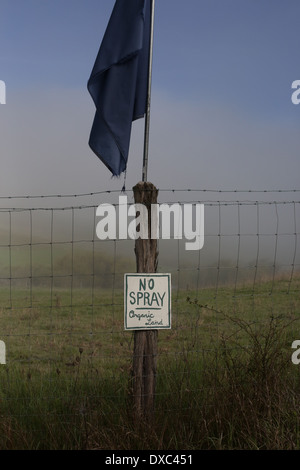A sign on a fence near a northern California farm stating "no spray, organic land". Stock Photo