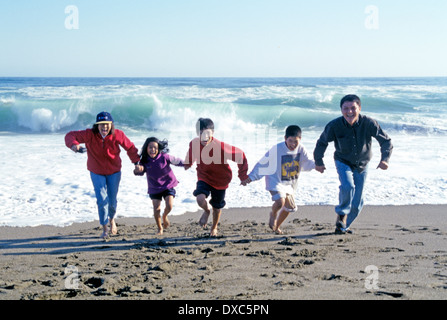 Chinese family on holiday having fun running from the surf on Stinson Beach California Stock Photo