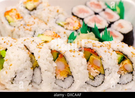 Take out or take away container of fresh sushi rolls - dynamite roll, tuna roll and California roll. Stock Photo