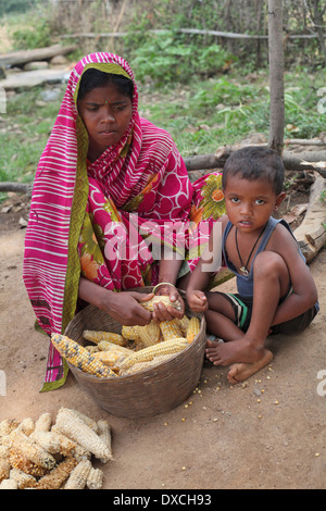 Woman separating the corn from the corncob while the child looks on. Santhal tribe, District Hazaribaug, Jharkhand Stock Photo