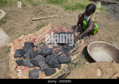 Lady breaking coal in pieces for transport to households as a source of fuel. Kurmali tribe. Ranchi District Jharkhand Stock Photo