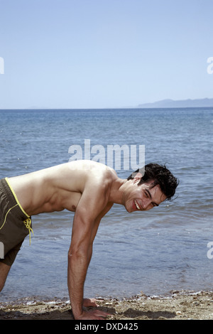 Young adult male doing pushups on beach Stock Photo