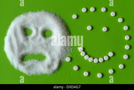 Berlin, Germany. 19th Feb, 2014. Illustration - A smiling face (R), put together from pills made of stevia and a sad face, made from a pile of sugar, are on display next to each other on a green table in Berlin, Germany, 19 February 2014. Stevia works as a sweetners and sugar substitute for patients suffering from diabetes. Photo: Jens Kalaene/dpa/Alamy Live News Stock Photo