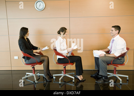 Office workers sitting in chairs with documents Stock Photo