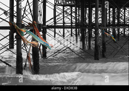 Waves splashhing under the pier with debris blowing in the wind after a storm at Cromer in Norfolk England Stock Photo