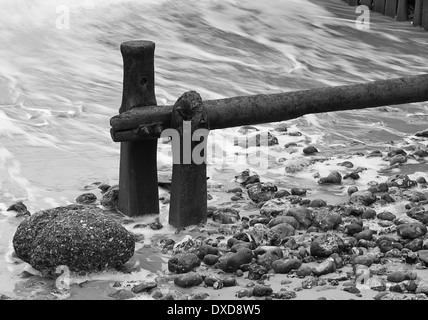 Sea swirling around the groynes at Cromer beach in Winter in Norfolk England Stock Photo