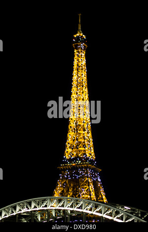 France most known monument, Eiffel tower, illuminated against dark night sky with bridge structure on the foreground.
