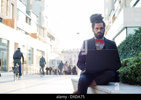 Stylish elegant dreadlocks businessman using notebook in business landscape Stock Photo