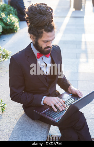 Stylish elegant dreadlocks businessman using notebook in business landscape Stock Photo