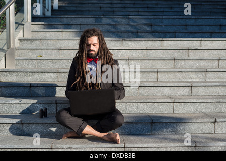 Stylish elegant dreadlocks businessman using notebook in business landscape Stock Photo
