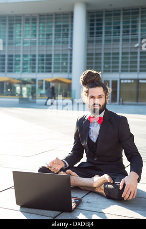 Stylish elegant dreadlocks businessman using notebook in business landscape Stock Photo
