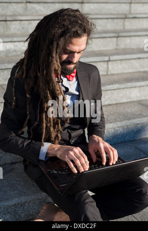 Stylish elegant dreadlocks businessman using notebook in business landscape Stock Photo
