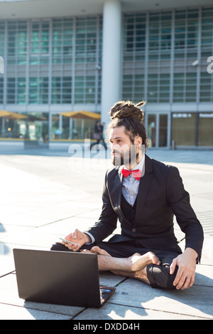 Stylish elegant dreadlocks businessman using notebook in business landscape Stock Photo